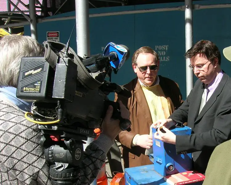 Journalist Donn Pearlman (left) and author Scott Travers (right) show cameras the 1909-S VDB penny about to be spent in circulation at a New York City street vendor. 