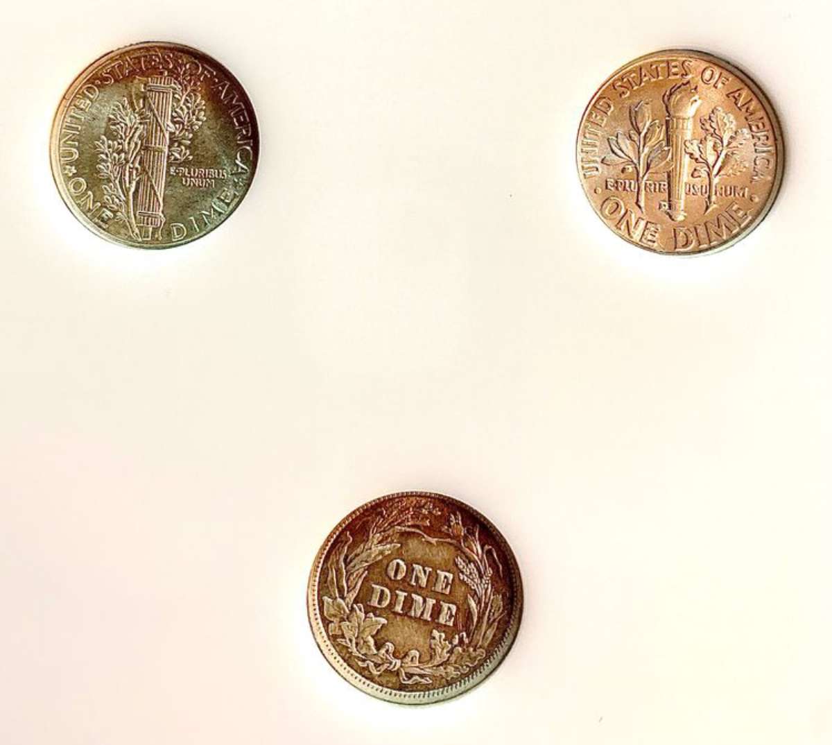 Clockwise are seen the reverse of the Mercury dime, Roosevelt dime, and Barber dime. 