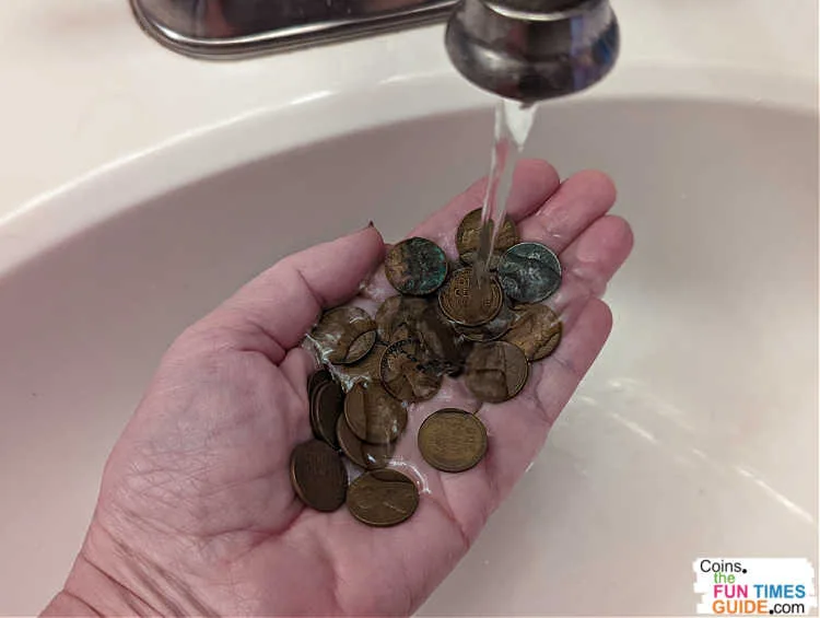 This is the safest way to clean coins... simply hold them under a stream of water to remove debris. Then, pat each coin dry, one by one.