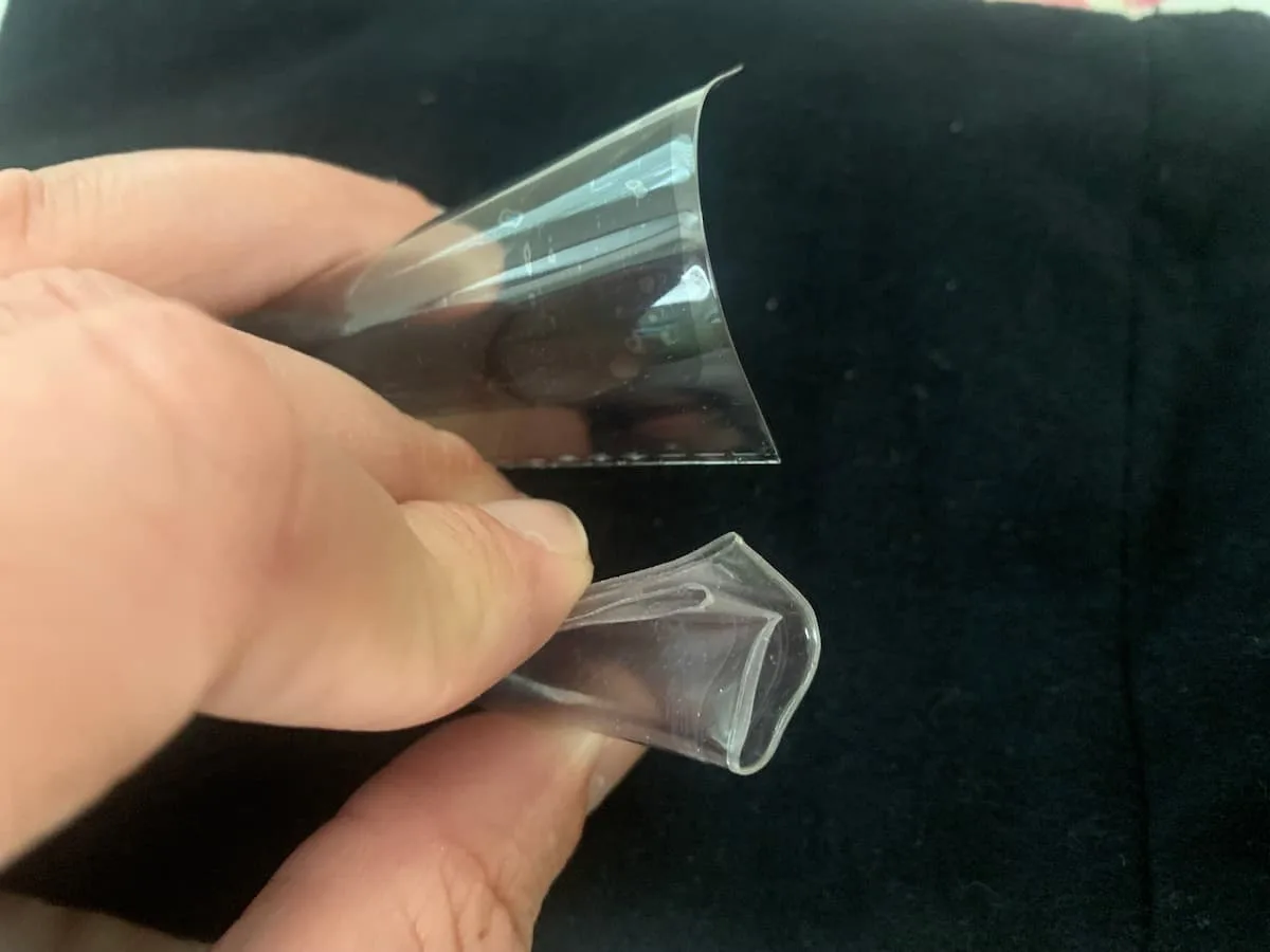 The top flip is a non-PVC SAFLIP made from polyethylene terephthalate and would crack if I bent it any further. The bottom coin flip is highly suspect for PVC because its slightly greasy, soft, and can easily bend and fold without cracking. 