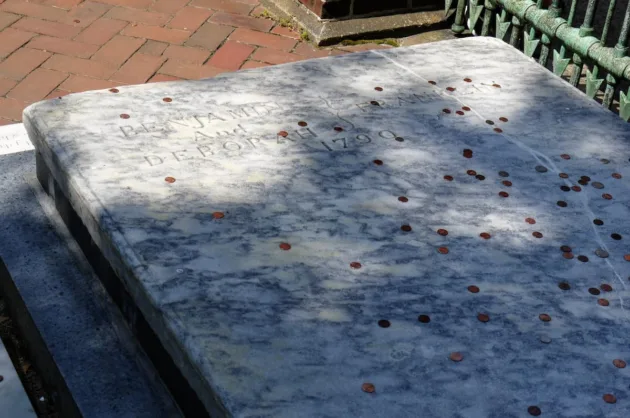 The tradition behind why people put coins on graves is fascinating and filled with meaning. Here, pennies are seen on Ben Franklin's grave in Philadelphia.